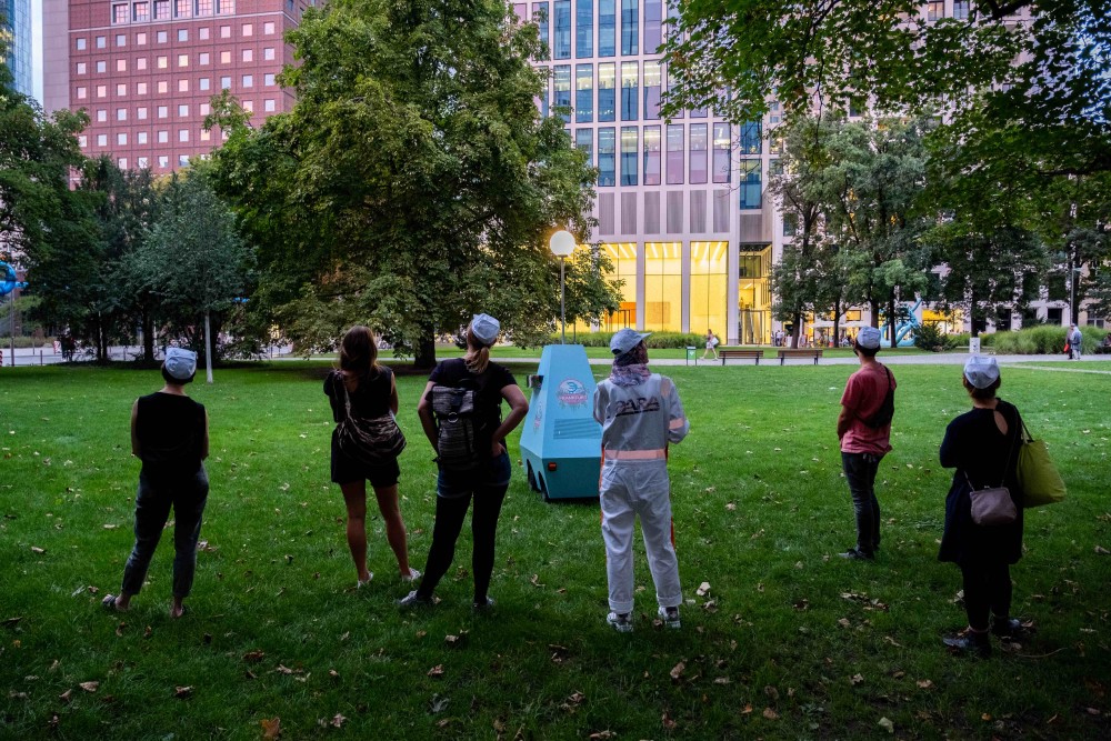 A group of people and a robot in a public park.