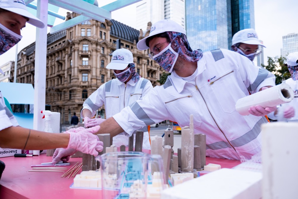 A group of people in lab suits working on architectural clay models